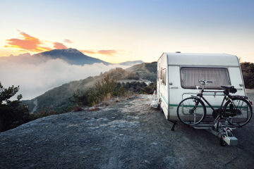 Wohnwagen-mit-dem-Fahrrad-in-den-Alpen-bei-Sonnenaufgang