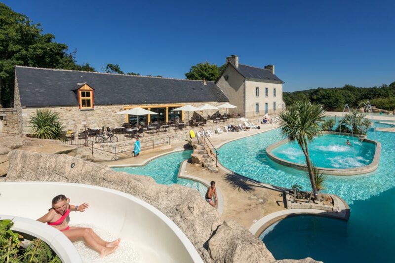 Poolbereich mit Wasserrutsche und Liegestuehlen auf dem Campingplatz