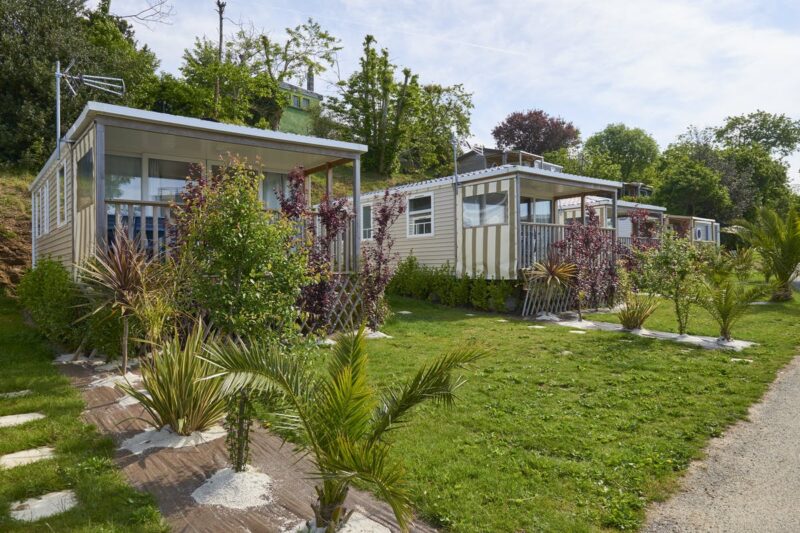 Mobilheime vom Campingplatz mit Veranden auf grüner Wiese