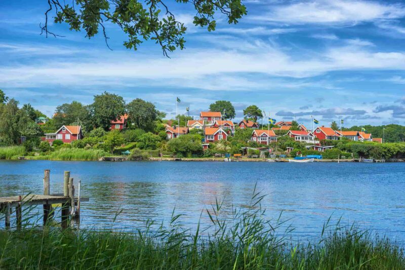 KARLSKRONA, SCHWEDEN. Typische rote schwedische Holzhäuser mit Nationalflagge in der Stadt Karlskrona