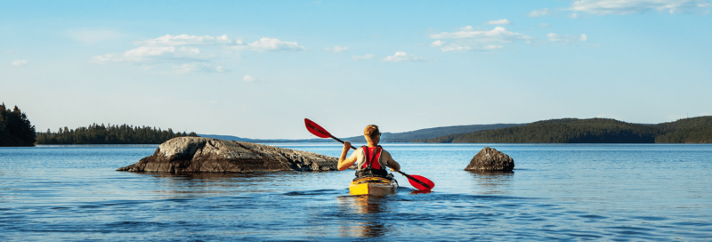 Kanu Paddler auf einem See in Schweden zwischen Felsen