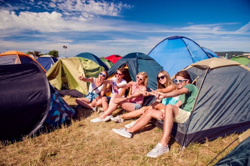 Teenagers sitting on the ground in front of tents © Halfpoint